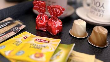 Un plateau contenant divers aliments, notamment des bonbons emballés, une tasse de café et des sachets de thé Lipton.