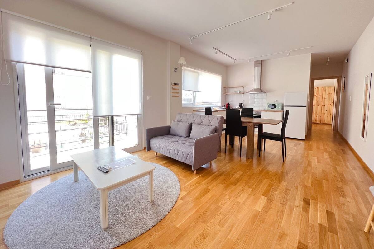 A modern apartment with a living room, dining area, kitchen, and a balcony.
