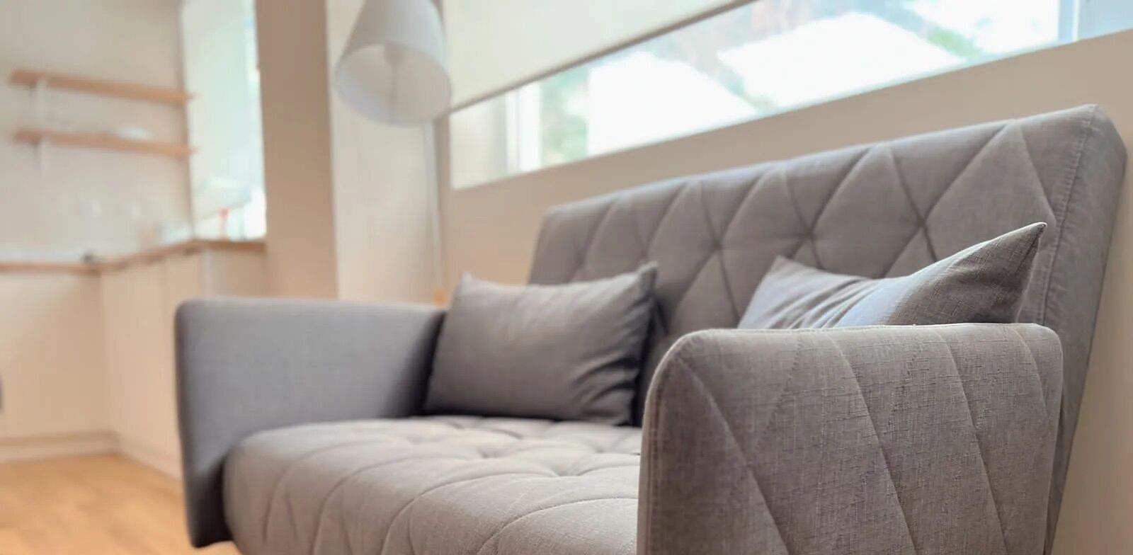 Una sala de estar moderna con un sofá gris y una lámpara colgante.