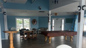 A spacious room with a pool table, a billiards table, and a dining area with chairs and a table. - The Moorings Hotel and Marina  (Carrabelle)