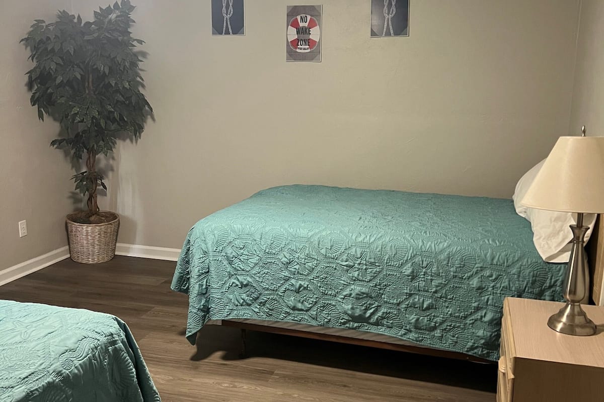 Ein Schlafzimmer mit zwei Betten, einem Deckenventilator, einer Topfpflanze und einem Schild mit der Aufschrift 'No Wake Zone'.