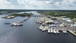 A marina with multiple docks and boats, connected by walkways, and surrounded by greenery and buildings. - The Moorings Hotel and Marina  (Carrabelle)