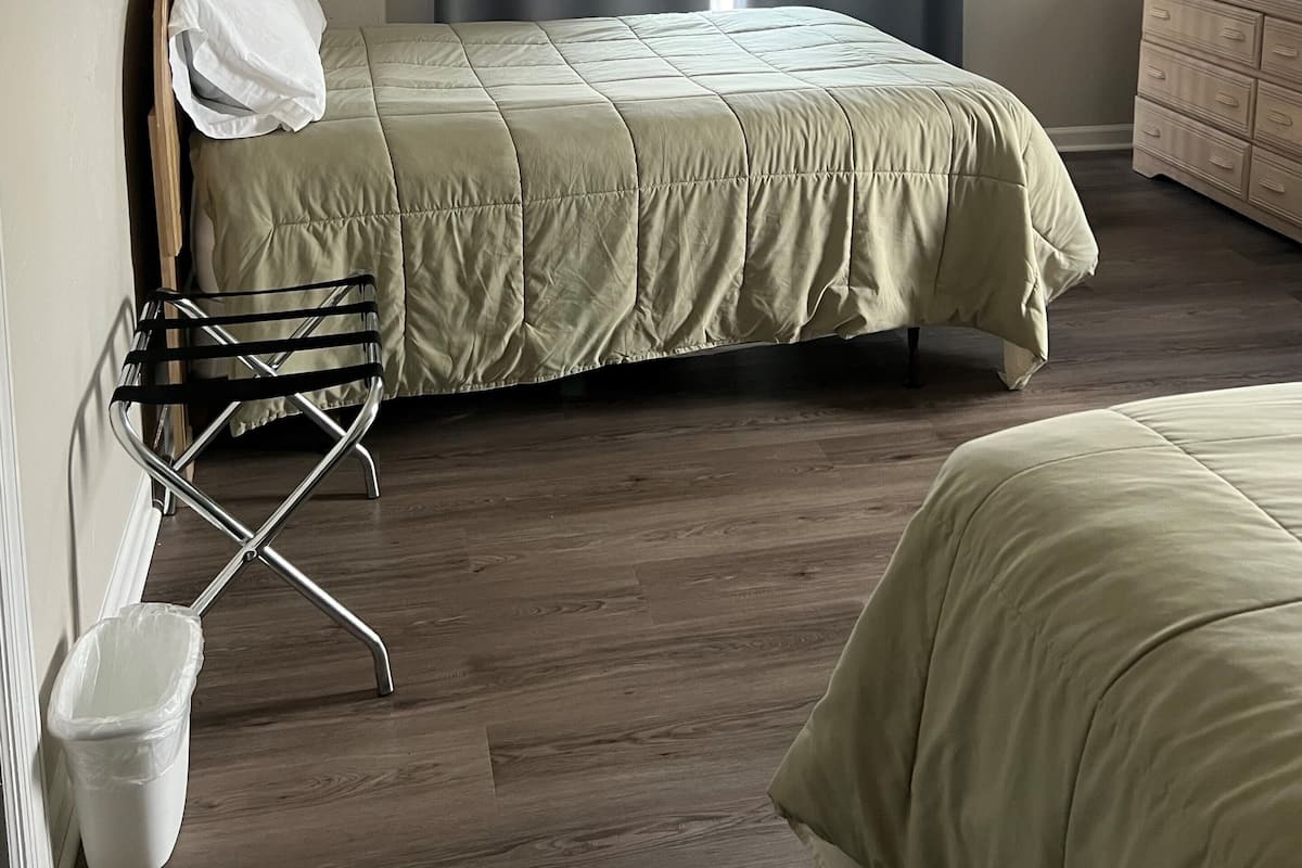 Ein Schlafzimmer mit Bett, Schminktisch, Stuhl und einem Fenster mit Vorhängen.