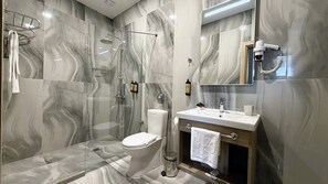 A bathroom with a glass-enclosed shower, a toilet, a sink with a mirror, and a towel rack. - Evelin Deluxe House (Plovdiv)