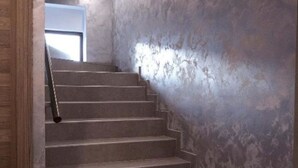 Una escalera con una pared texturizada y una puerta de madera a la izquierda.