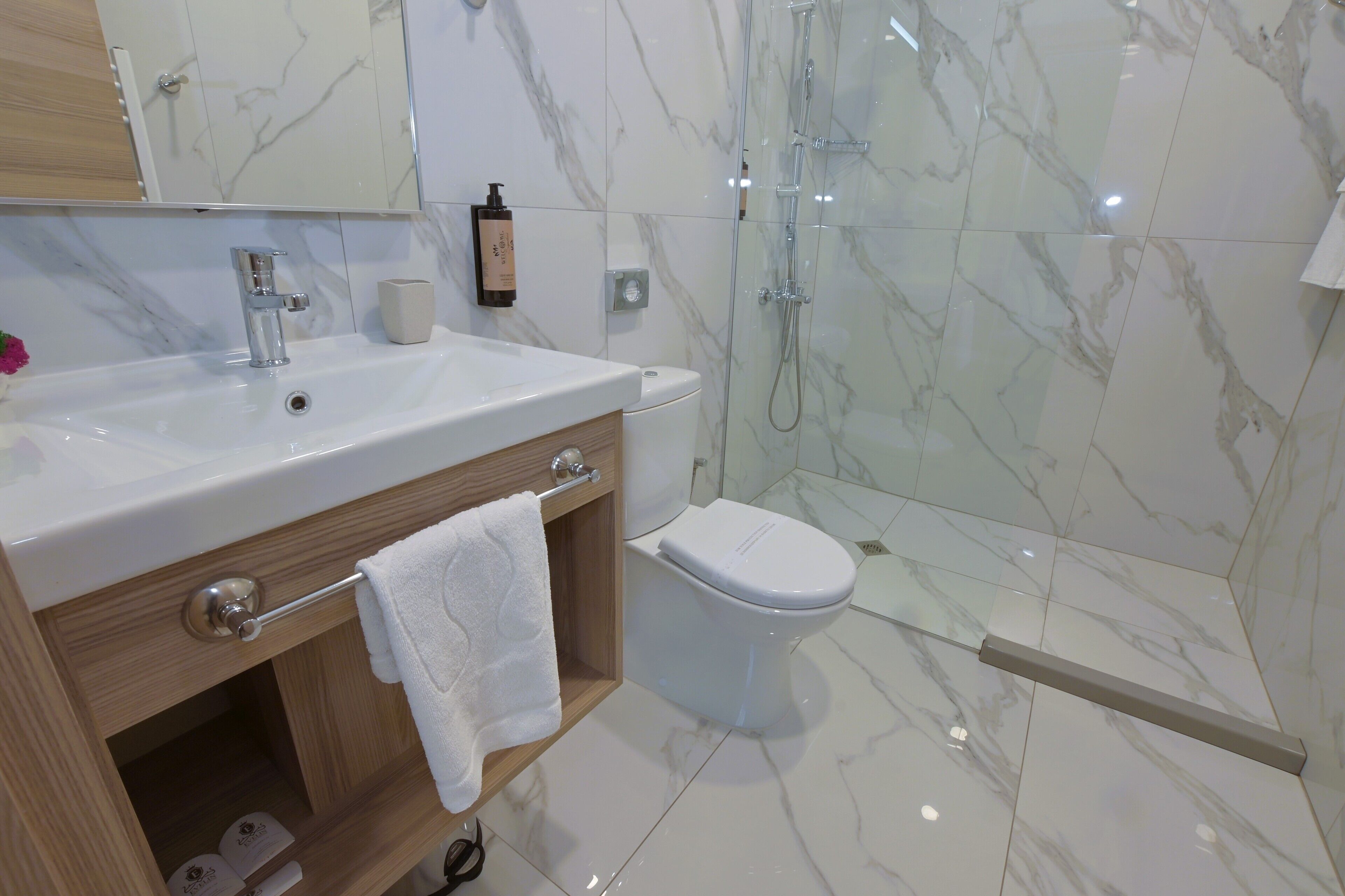 A bathroom with a marble sink, a toilet, and a glass-enclosed shower.