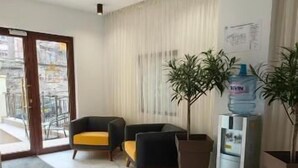 Un hall espacioso con suelo de mármol, una recepción, dos sillones y plantas en macetas.