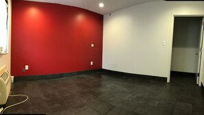 Une pièce avec un mur d’accent rouge, un sol carrelé foncé et une porte blanche donnant sur une autre pièce.