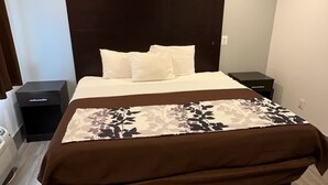 Une chambre d’hôtel avec un grand lit, une table de chevet et une commode.