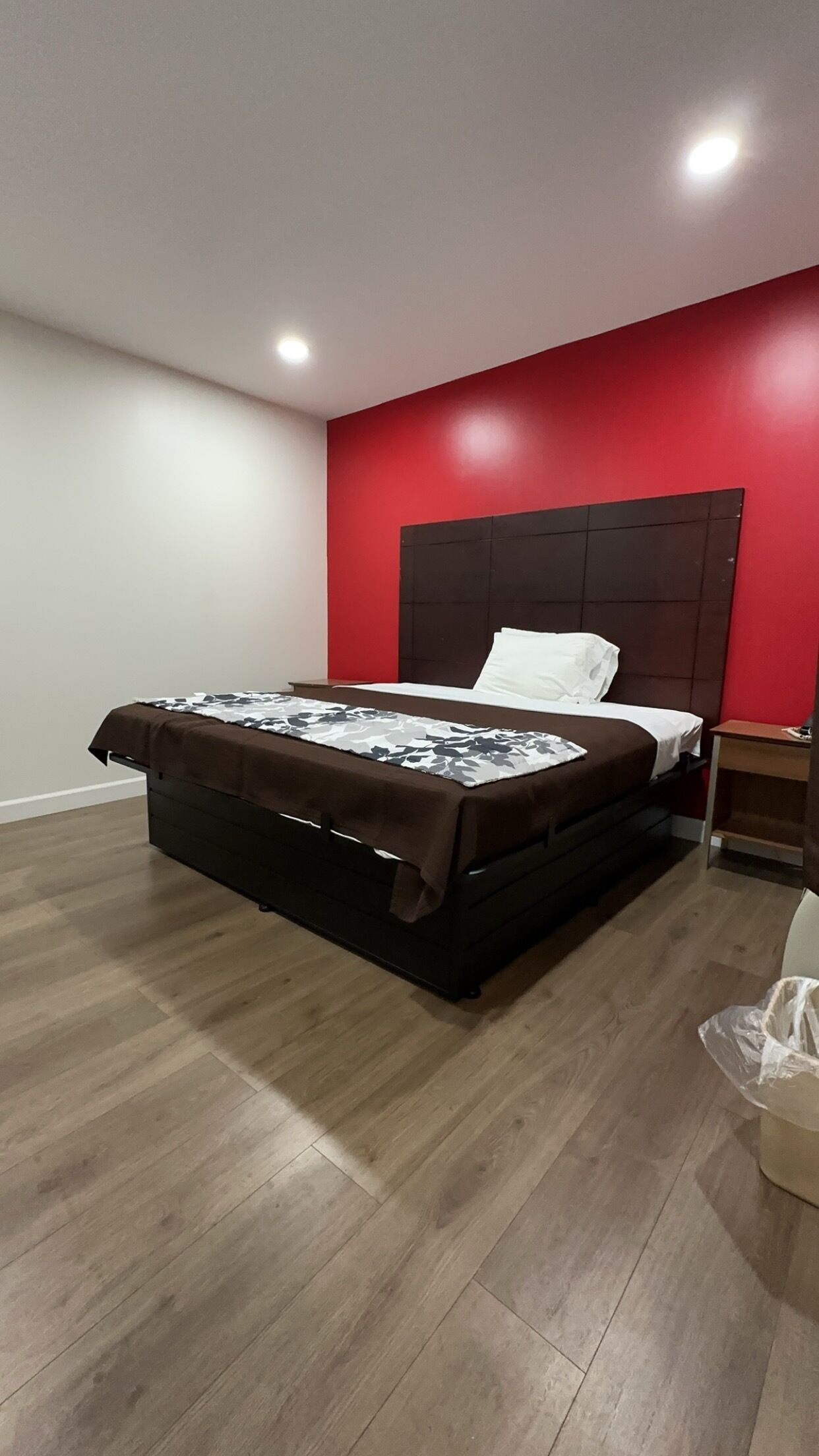 A bedroom with a bed, a nightstand, and a red accent wall.