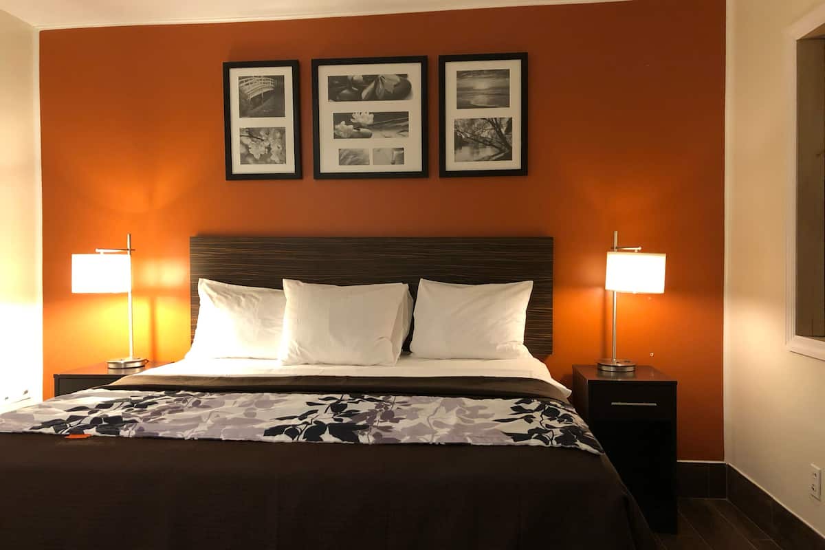 A hotel room with a large bed, two bedside tables with lamps, and three framed pictures on the wall.