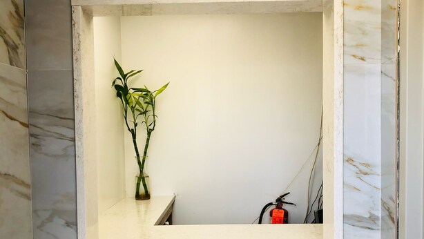 Une salle de bain avec un mur en marbre et un meuble-lavabo blanc.