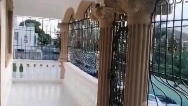 A corridor with white tiled flooring, ornate columns, and a metal railing. - Heart of DR, 20 Min from Airport (Santo Domingo Este)