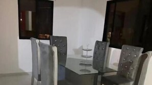 A dining area with a glass table and four upholstered chairs. - Heart of DR, 20 Min from Airport (Santo Domingo Este)