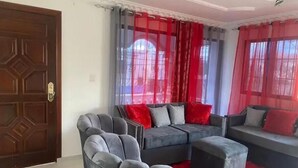 A living room with a grey sofa set, a grey armchair, and a red rug. - Heart of DR, 20 Min from Airport (Santo Domingo Este)