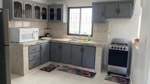 A compact kitchen with grey cabinets, a microwave, a sink, and a stove. - Heart of DR, 20 Min from Airport (Santo Domingo Este)