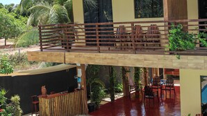 A two-story building with a balcony, outdoor seating, and a swimming pool. - Harmonia Flats (Tibau do Sul)