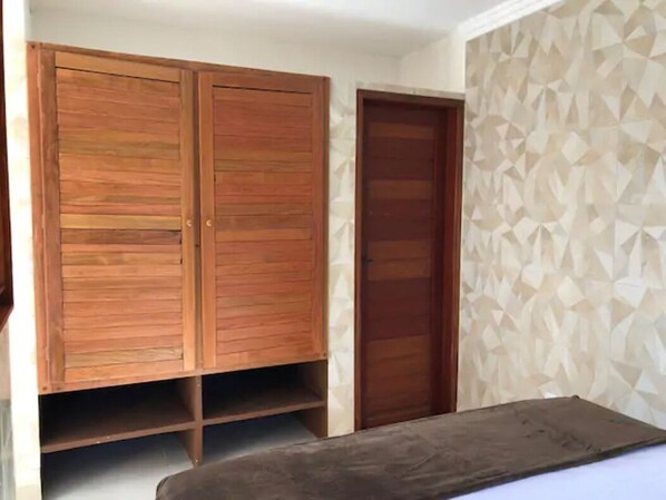 Une pièce avec une armoire en bois, une porte et un mur orné d’un motif.