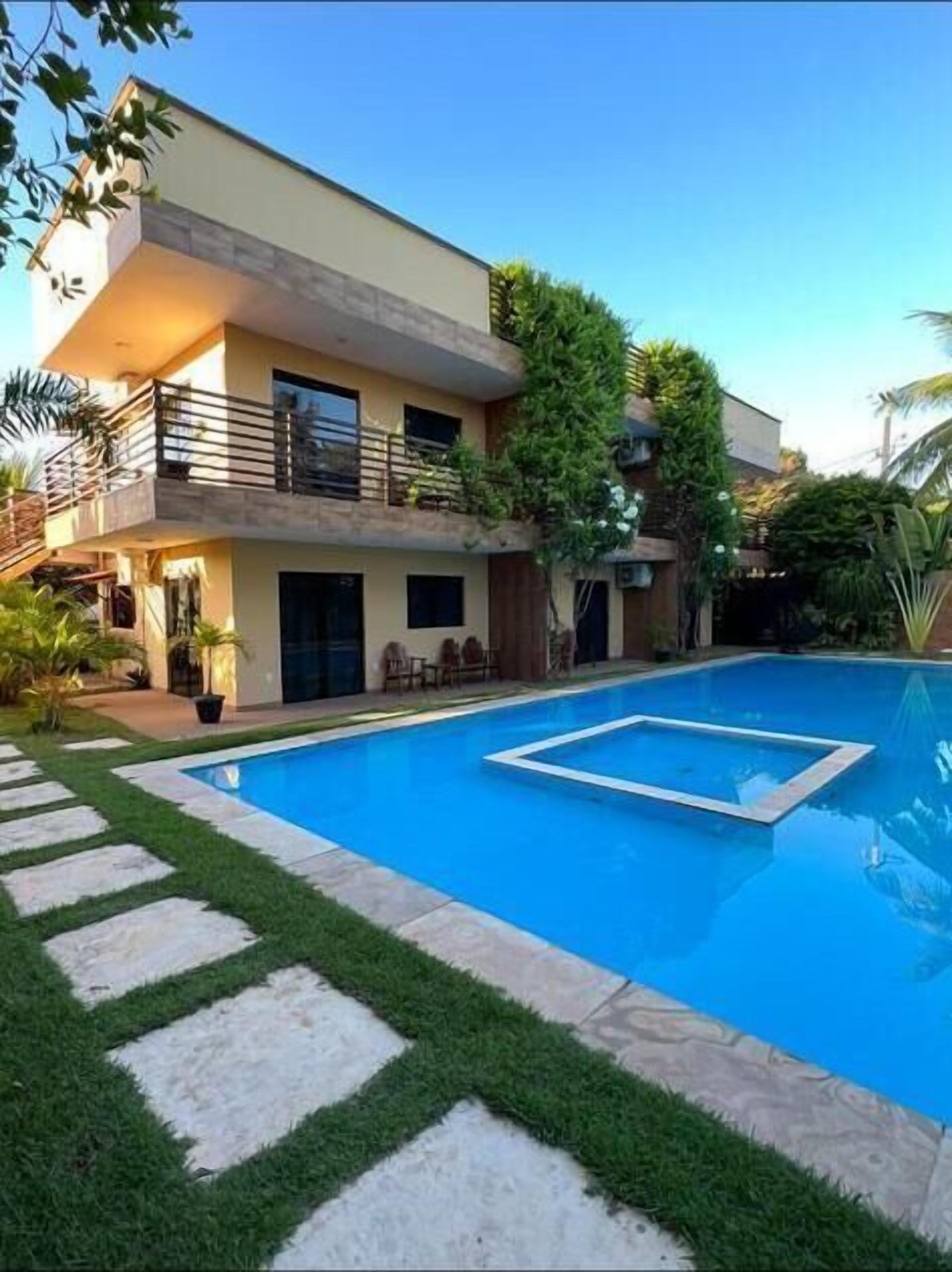 A two-story house with a swimming pool, a balcony, and a garden.