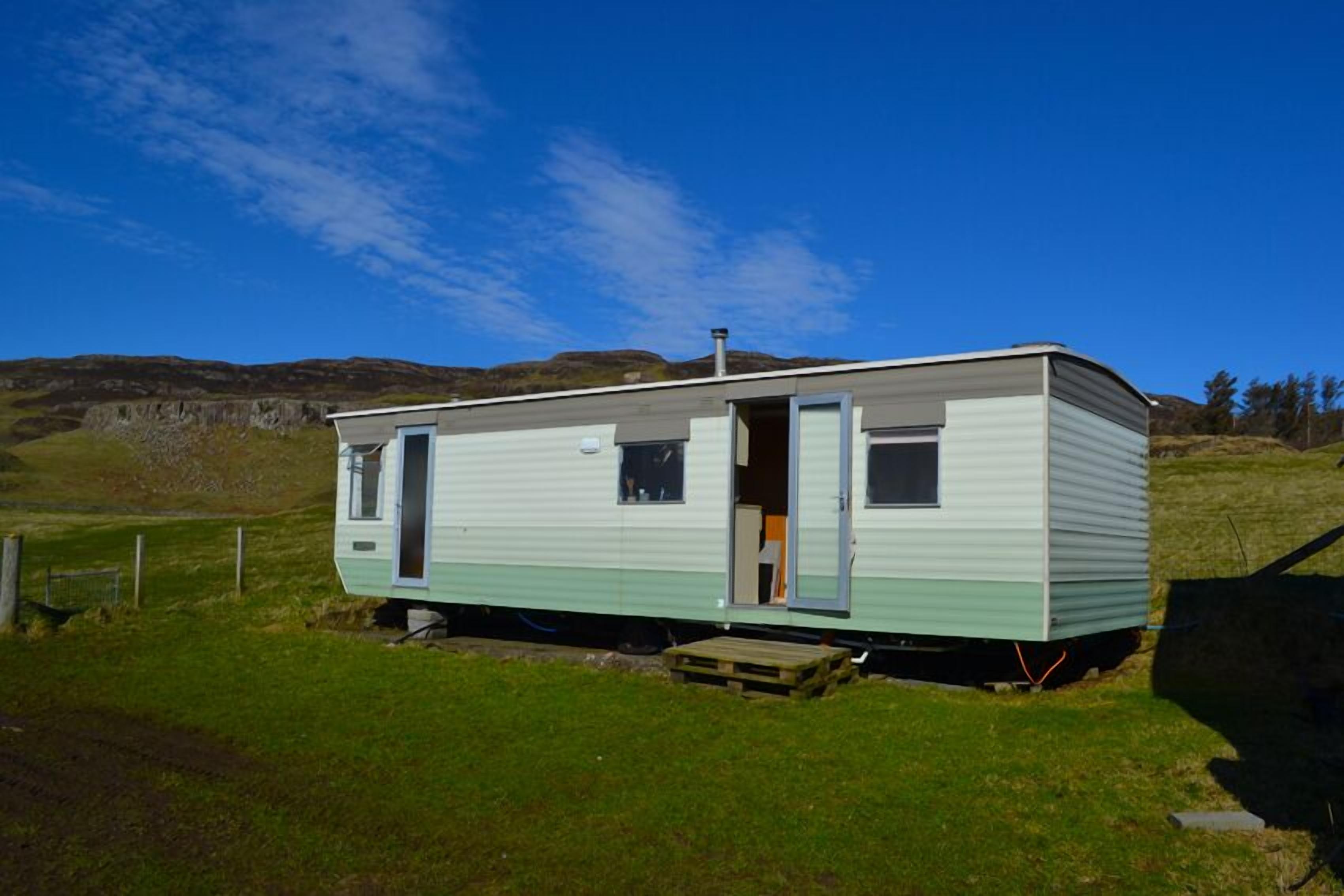 A single-story mobile home with a door open, revealing a small interior space.