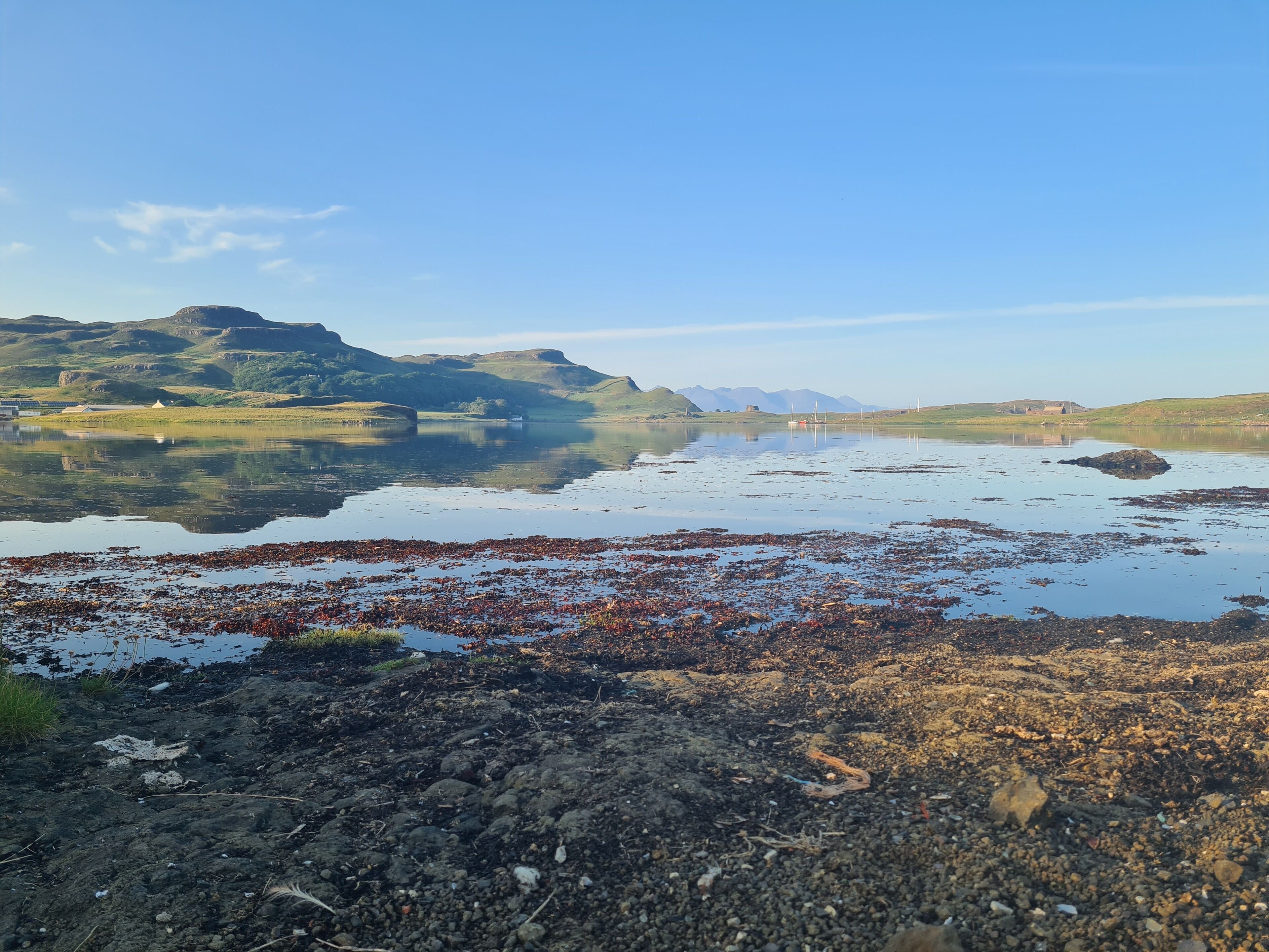 A lake with surrounding hills and a clear sky.