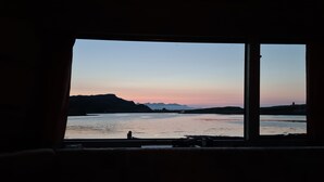 A view from a window with a table in the foreground featuring three lit candles. - Canna Campsite (Isle of Canna)