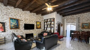 A stone-walled living room with a fireplace, leather sofas, a television, and a bookshelf.