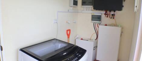 A compact laundry room with a washing machine, a dryer, and a small cabinet with a television.