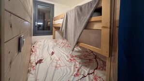 A bunk bed with a floral bedspread, a wooden wardrobe, and a mirror on the wall. - 250m from ski slopes, terrace, tv, 24m², Serre Chevalier (La Salle-les-Alpes)