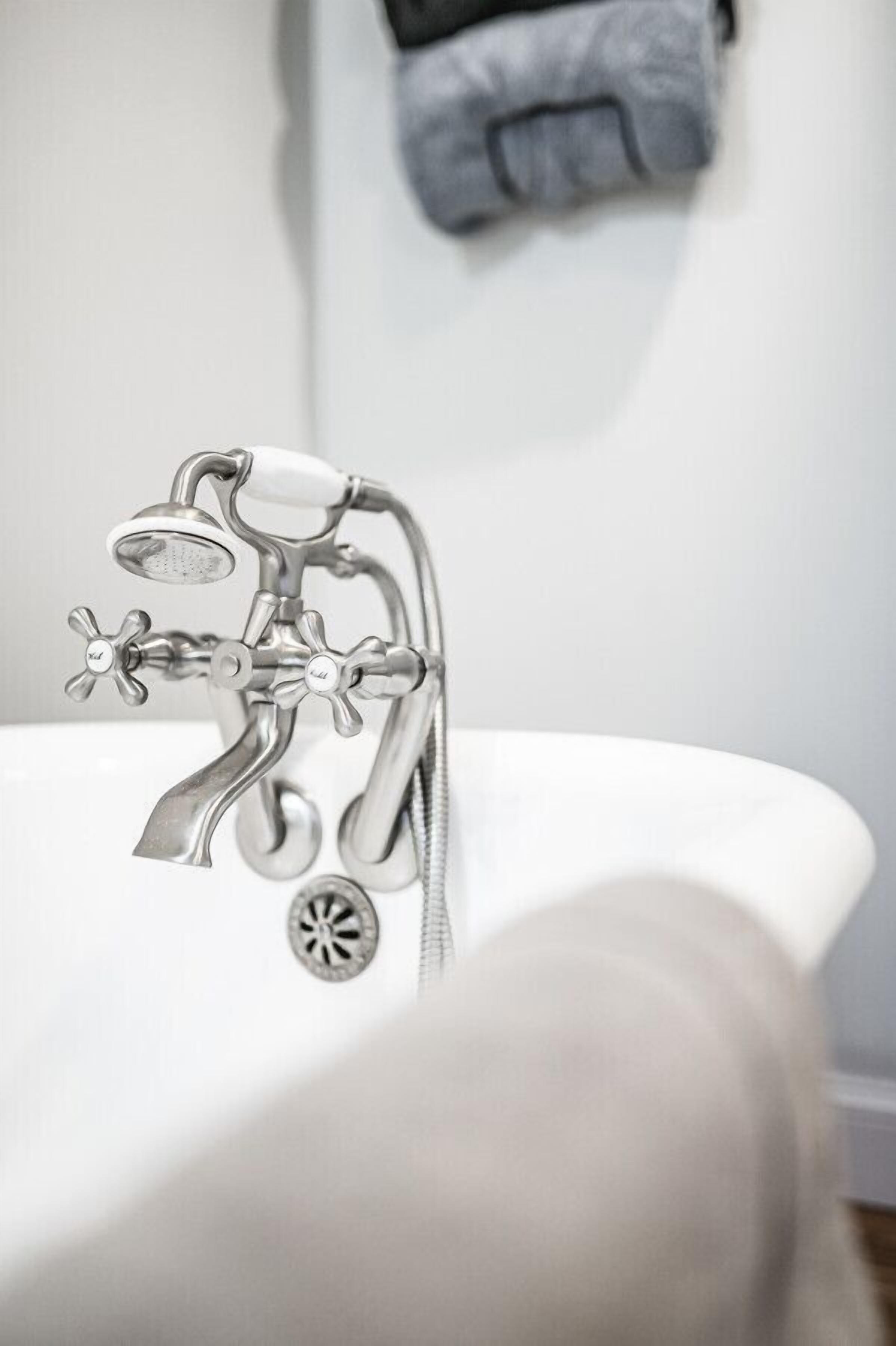 A bathroom with a modern faucet and showerhead, a towel rack, and a white sink.