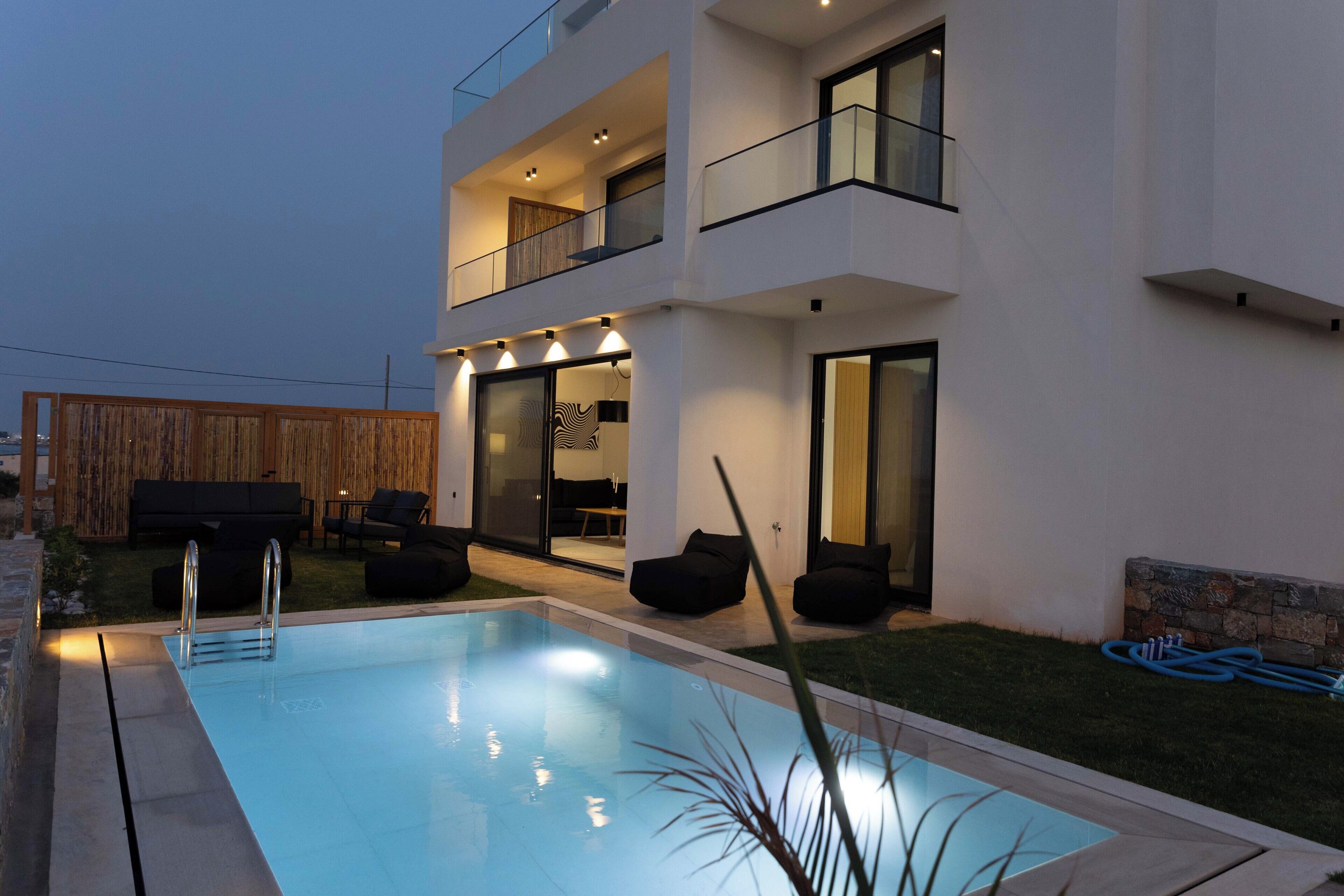 Une maison moderne à deux étages, dotée d’une piscine, d’un espace salon extérieur et d’un balcon bien éclairé.