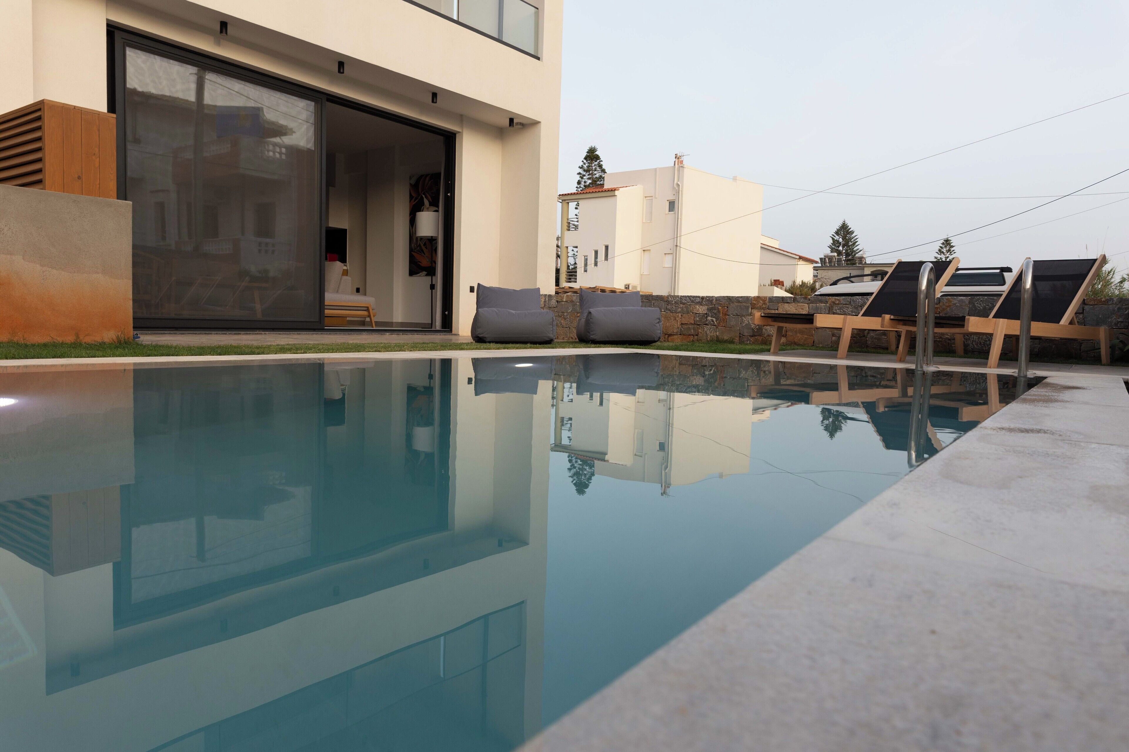 A modern house with a swimming pool, outdoor seating, and a large sliding glass door.