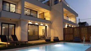 A modern two-story house with a swimming pool, outdoor seating, and a well-lit balcony. - Destino Luxury Villas Gournes (Hersonissos)