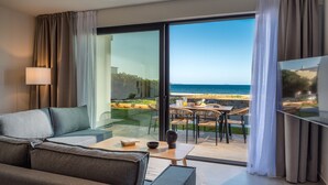 A modern hotel room with a large sliding glass door leading to a balcony with a view of the sea. - Destino Luxury Villas Gournes (Hersonissos)