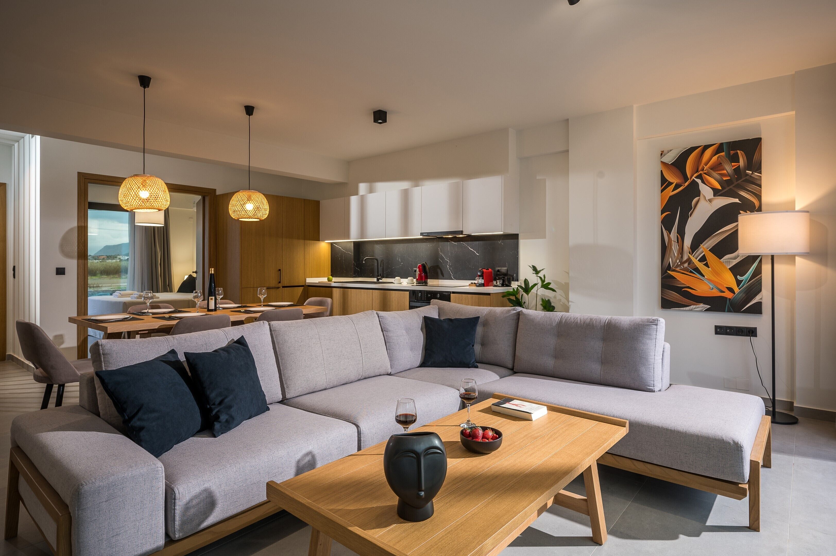 A modern living room with a grey sectional sofa, a wooden coffee table, and a dining area with a table and chairs.