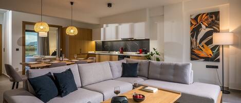 A modern living room with a grey sectional sofa, a wooden coffee table, and a dining area with a table and chairs.