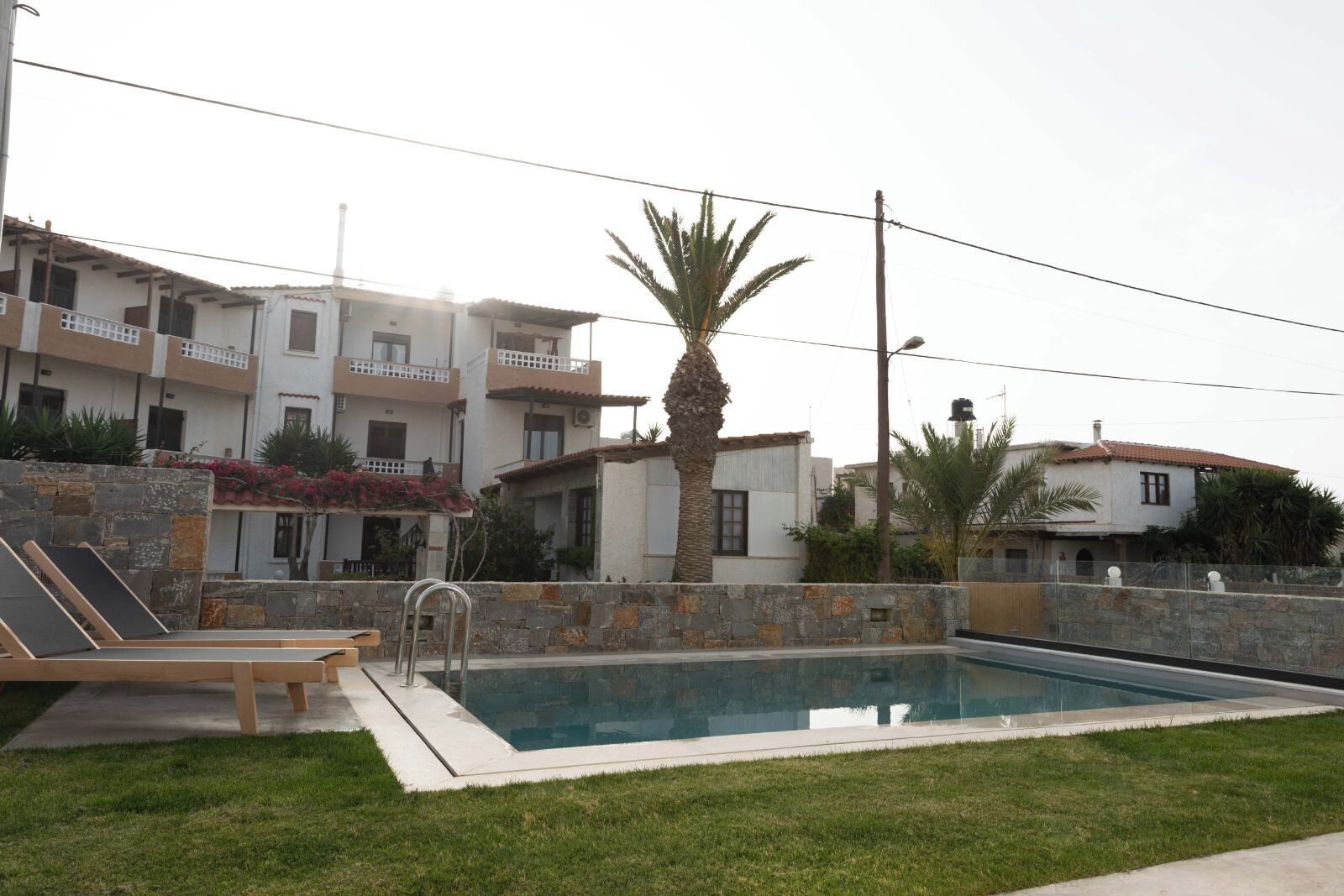 Piscina con pared de piedra y una palmera.