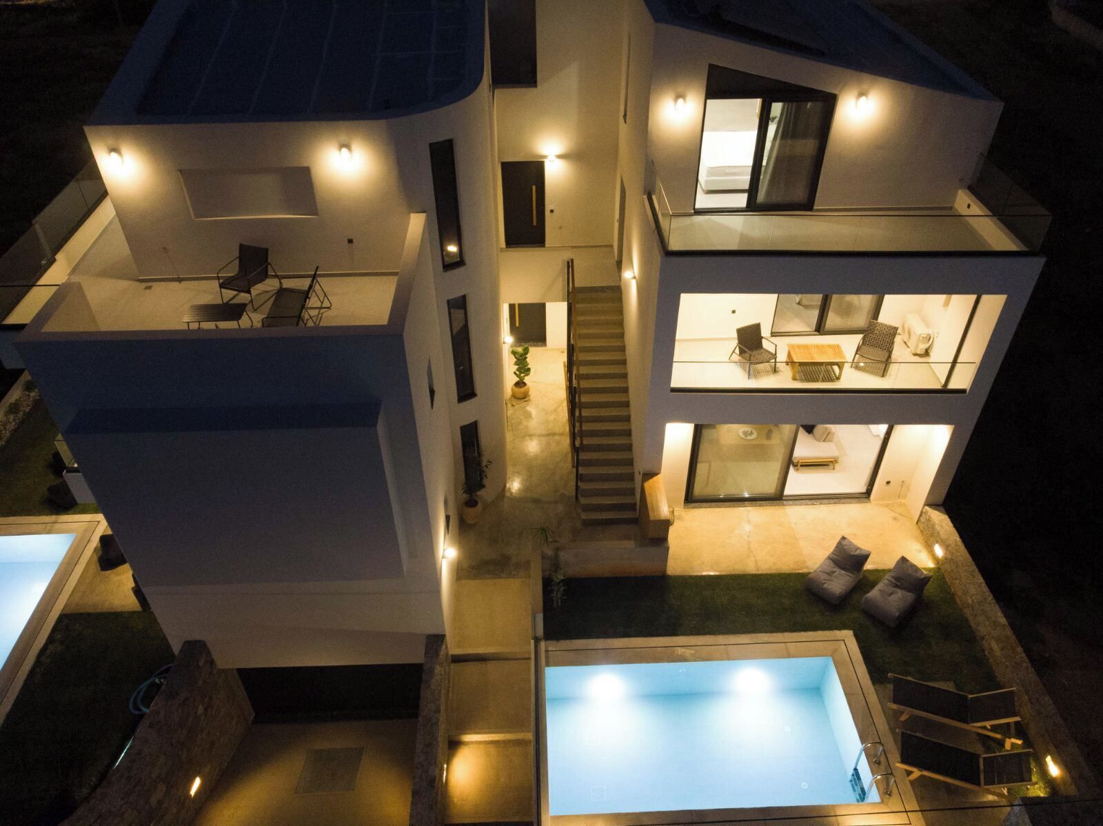 Una moderna casa a due piani con piscina, una scala e interni luminosi.
