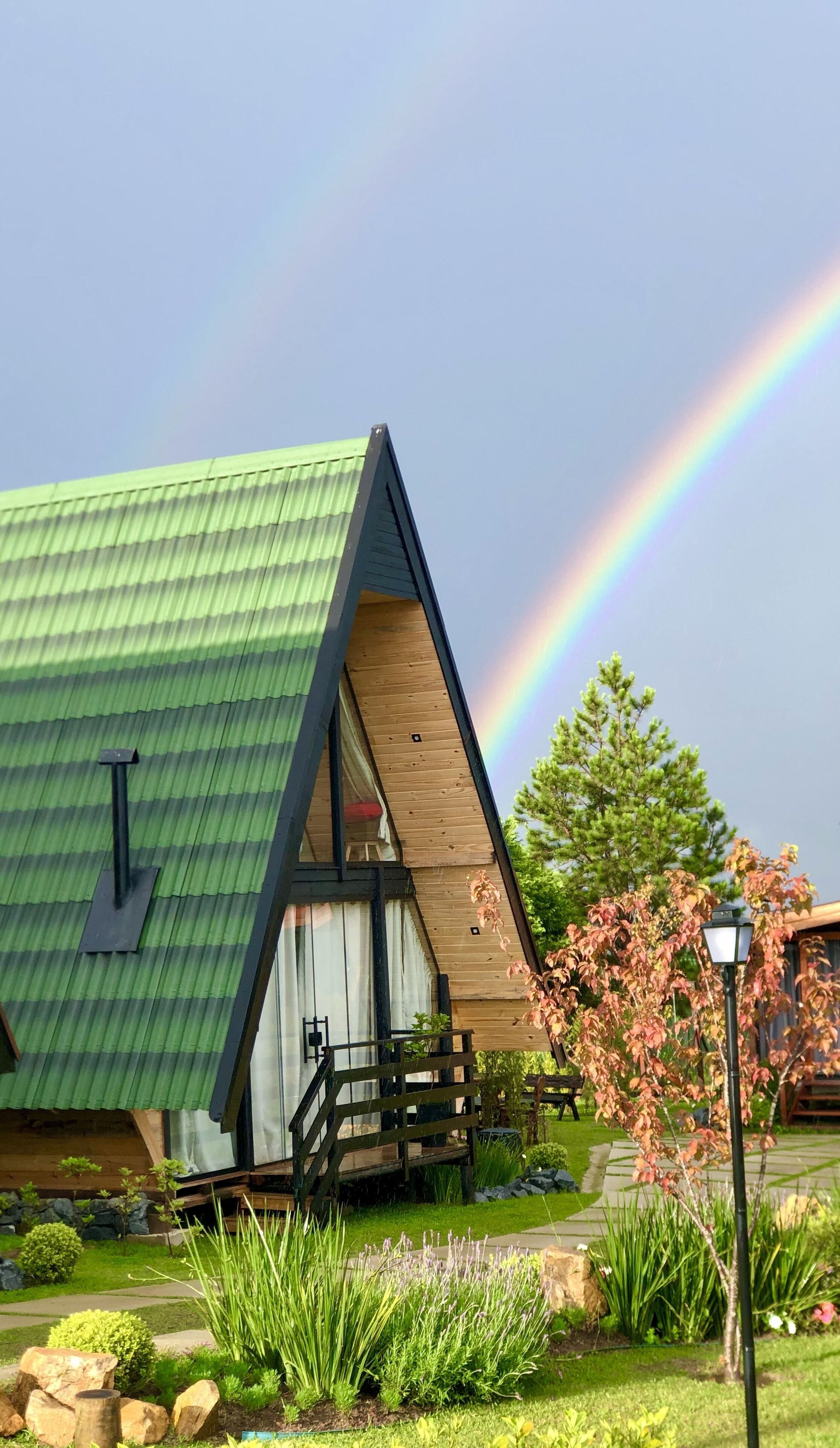 A triangular-roofed building with a wooden deck and a garden in front.