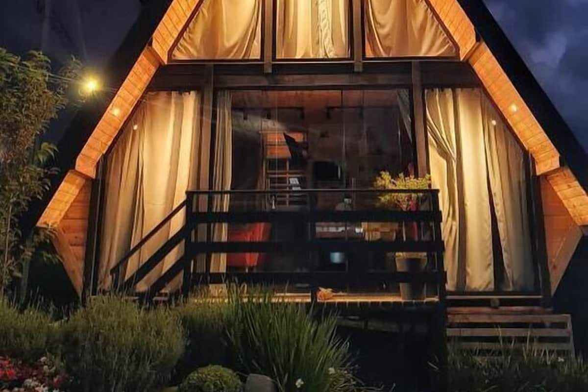 Un edificio de forma triangular con fachada de madera y ventanas grandes cubiertas por cortinas.
