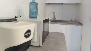 Eine kompakte Küche mit weißen Schränken, einem Spülbecken und einem Wasserspender.