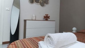 Ein Schlafzimmer mit einem Bett, einem Spiegel, einer Kommode und einer Wanddekoration.