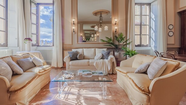 A spacious living room with a beige sofa set, a glass coffee table, and a large mirror. - Miranda's Home (Varenna)