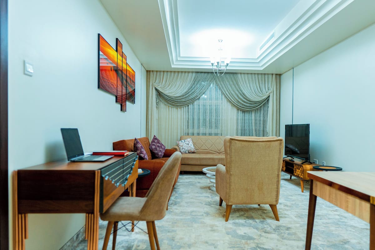 A living room with a sofa, a chair, a dining table, and a TV.