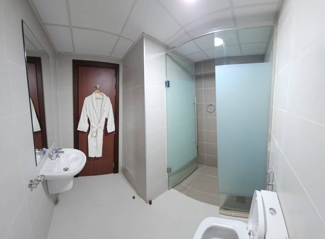 Ein modernes Badezimmer mit Waschbecken, Spiegel, Bademantel und einer Duschkabine aus Glas.