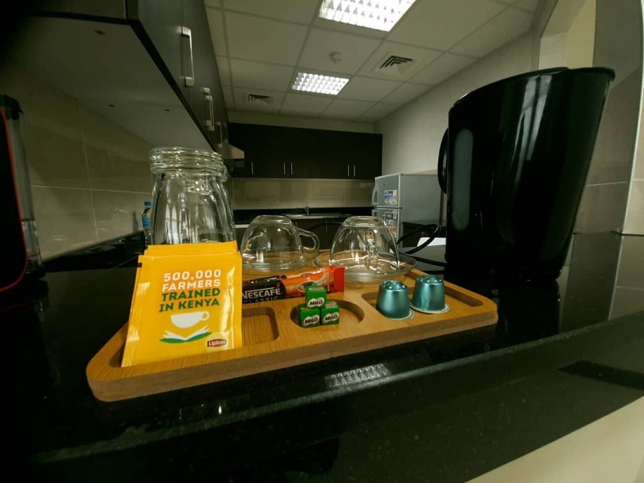 A kitchen counter with a coffee maker, a bag of coffee, and some coffee pods.