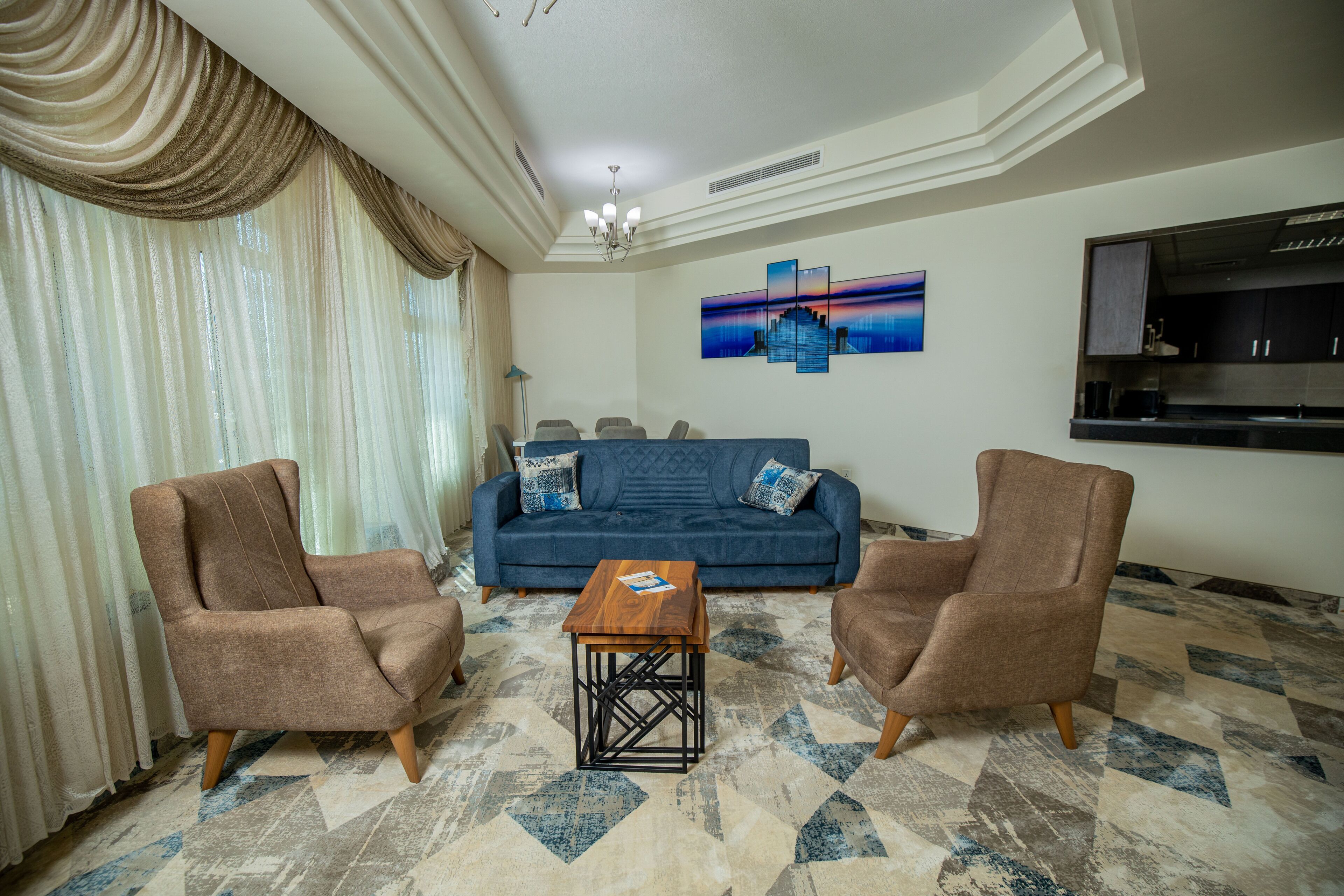 A living room with a sofa, two armchairs, a coffee table, and a wall-mounted TV.
