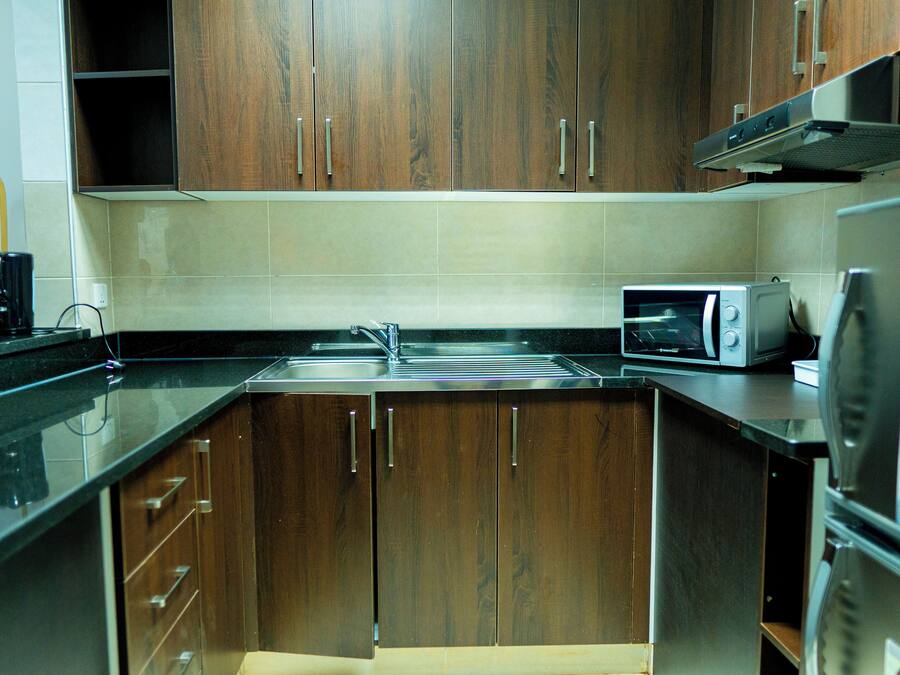 A kitchen with wooden cabinets, a microwave, and a refrigerator.