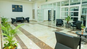 A spacious lobby with a marble floor, black seating, and potted plants. - NIAMEY MALL & RESIDENCE (Niamey)