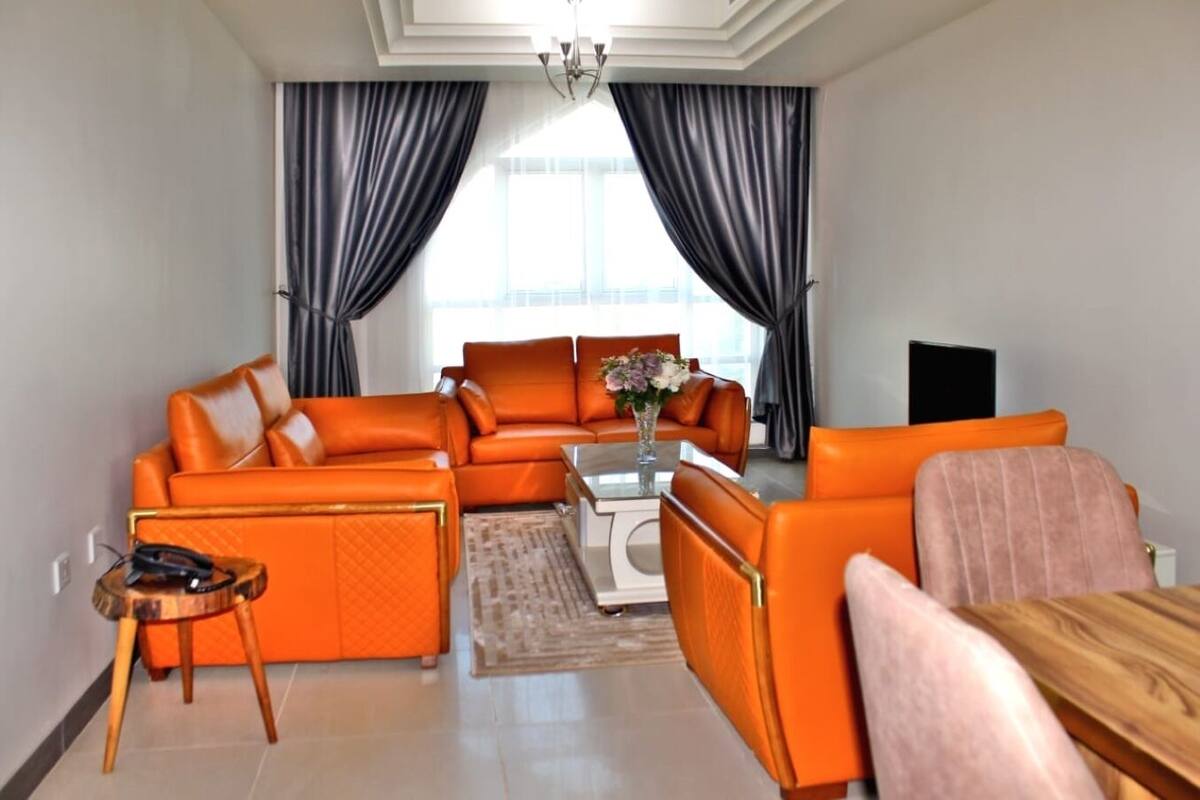 A living room with orange sofas, a coffee table, and a TV.